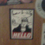 hand with middle finger extended and pointing at sticker covered speakers with goatse obey sticker.